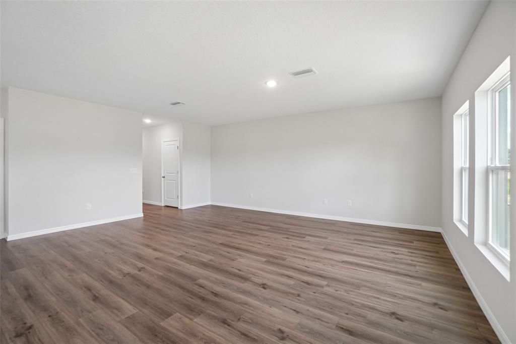 An empty room with light gray walls, wood-look flooring, and two windows on the right — 36564 SAGEMOOR DRIVE, ZEPHYRHILLS, FL