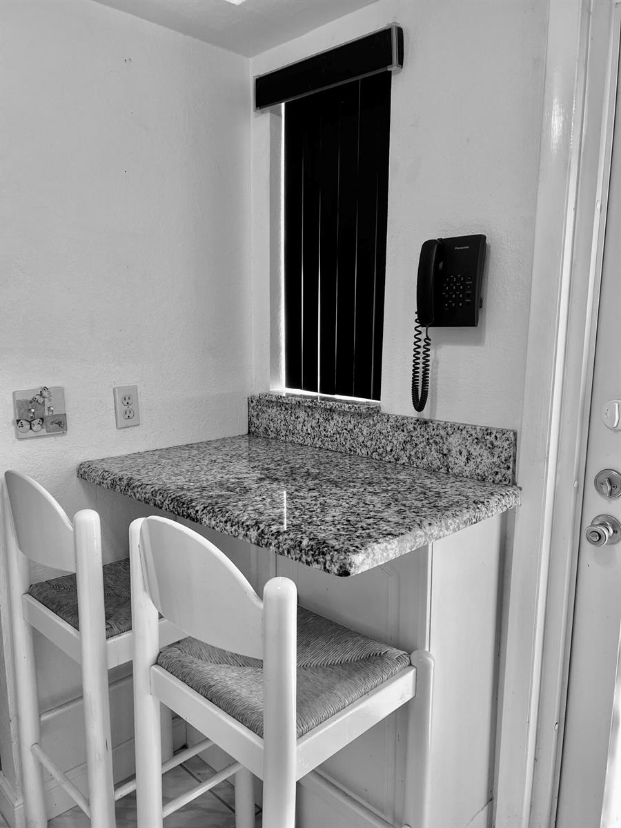 A small breakfast bar with granite countertops and two white chairs sits by a window — 2161 NE 1st Court # 102, Boynton Beach FL 33435, BOYNTON BEACH, FL