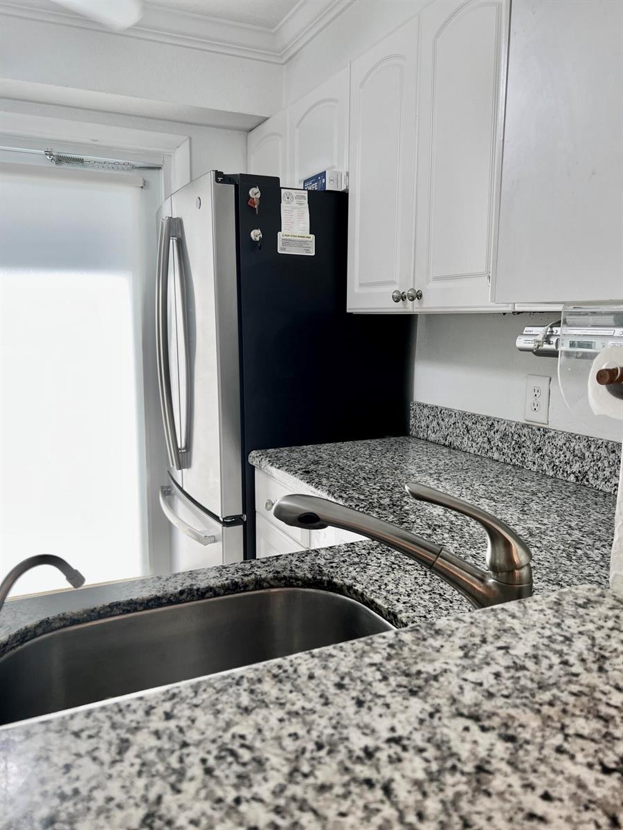 A kitchen features granite countertops, white cabinets, a stainless steel sink, and a black refrigerator — 2161 NE 1st Court # 102, Boynton Beach FL 33435, BOYNTON BEACH, FL