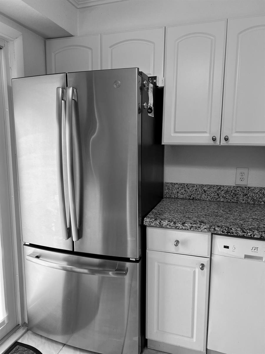 A stainless steel refrigerator stands next to white cabinets and a granite countertop — 2161 NE 1st Court # 102, Boynton Beach FL 33435, BOYNTON BEACH, FL