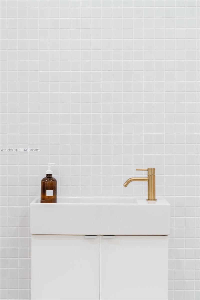 A white vanity with a gold faucet and soap dispenser sits against a tiled wall — 240-290 N Federal Highway, Fort Lauderdale FL 33301, FORT LAUDERDALE, FL