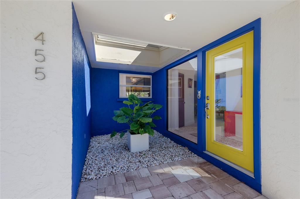 An entryway features a yellow door, blue walls, a skylight, and a potted plant — 455 S SHORE DRIVE, SARASOTA, FL