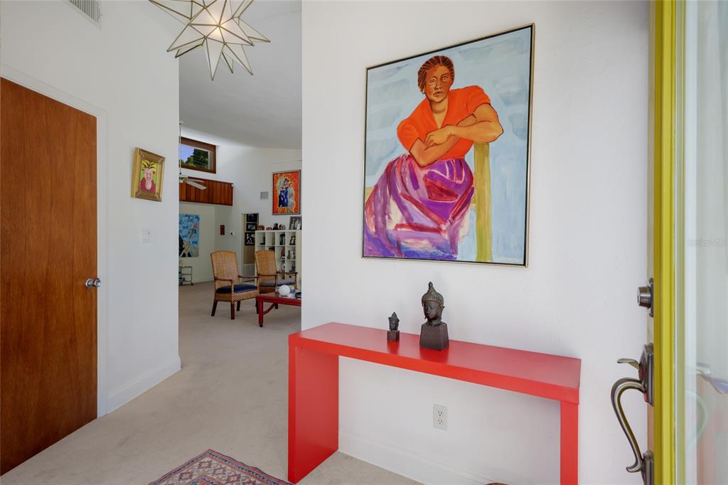 An entryway features a red console table, a large portrait painting, and a star-shaped light — 455 S SHORE DRIVE, SARASOTA, FL
