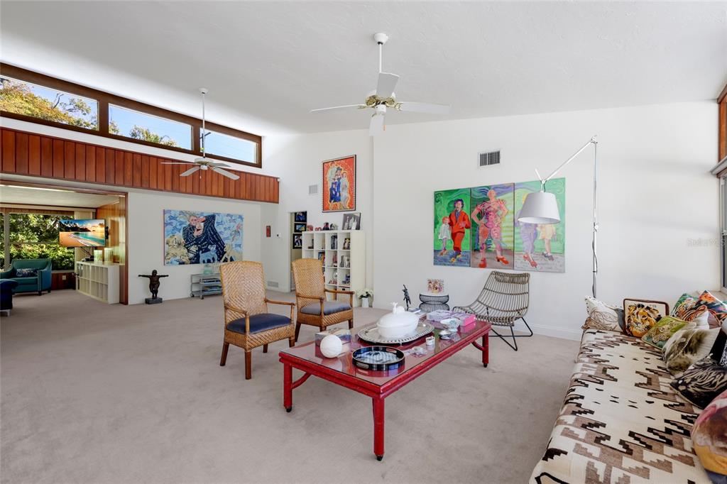 A spacious living room features high ceilings, a red coffee table, and colorful wall art — 455 S SHORE DRIVE, SARASOTA, FL