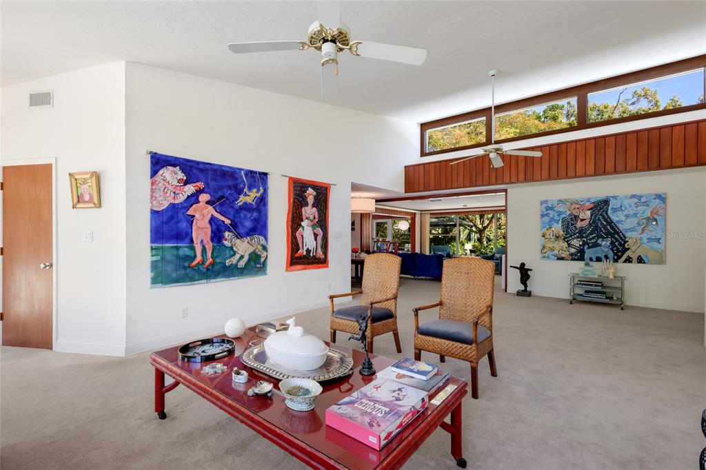 A living room features a red coffee table, two wicker chairs, and large wall art — 455 S SHORE DRIVE, SARASOTA, FL