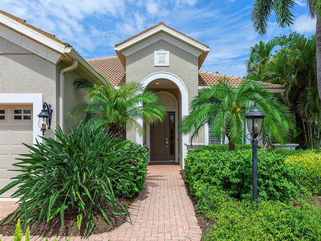 The front exterior of a house features a brick walkway leading to a covered entryway — 7210 LAKE FOREST GLEN, LAKEWOOD RANCH, FL