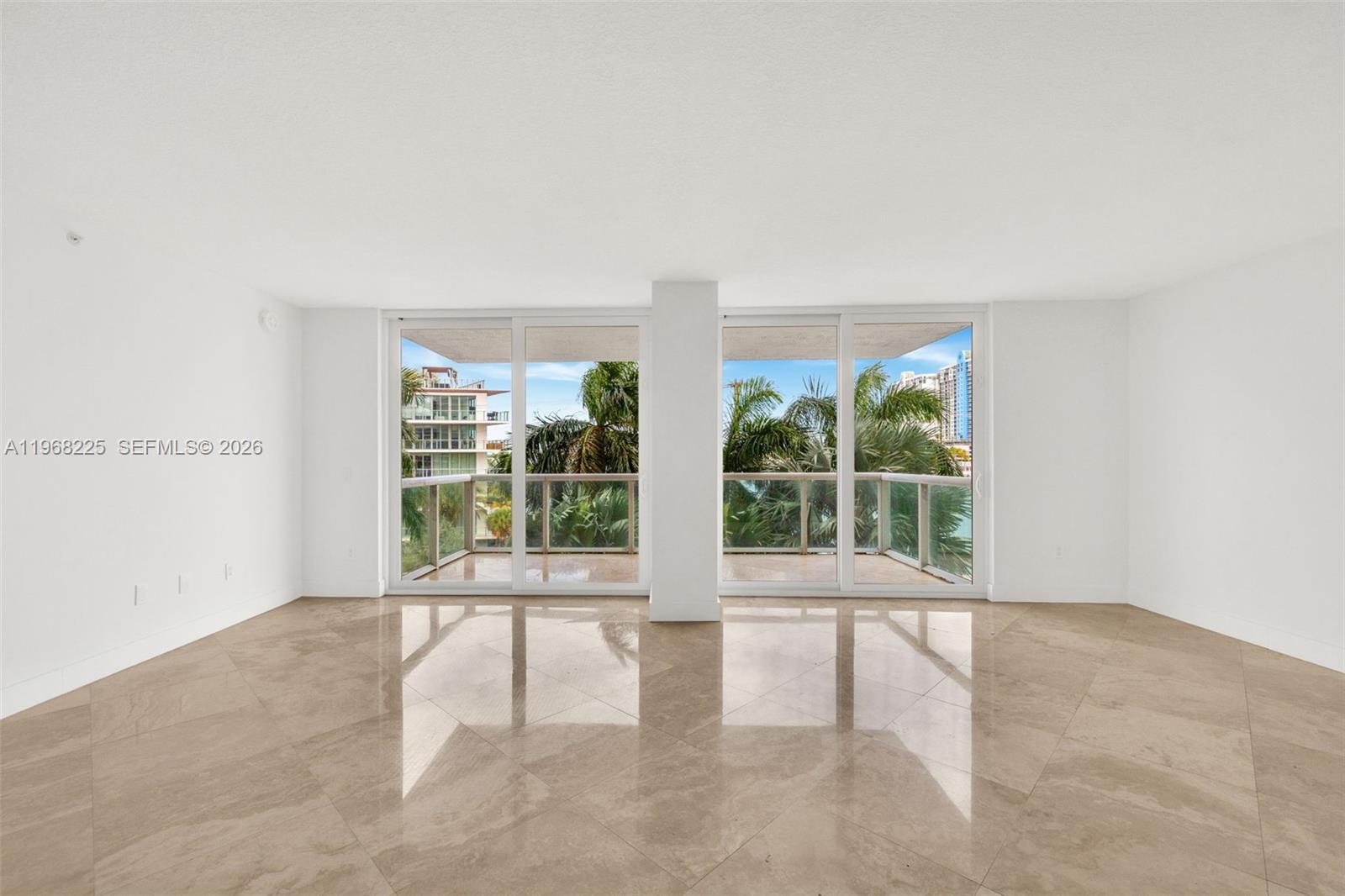 A bright, empty room features large sliding glass doors, a balcony, and polished tile floors — 10 Venetian Way # 403, Miami Beach FL 33139, MIAMI BEACH, FL
