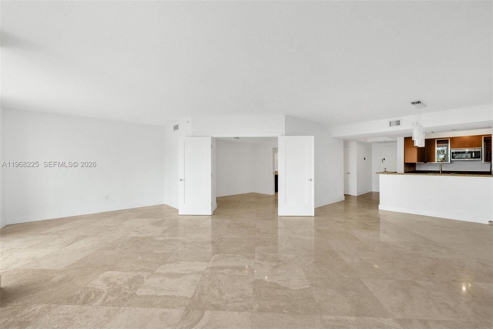 An open-concept living area features light-colored tile flooring, white walls, and an adjacent kitchen — 10 Venetian Way # 403, Miami Beach FL 33139, MIAMI BEACH, FL