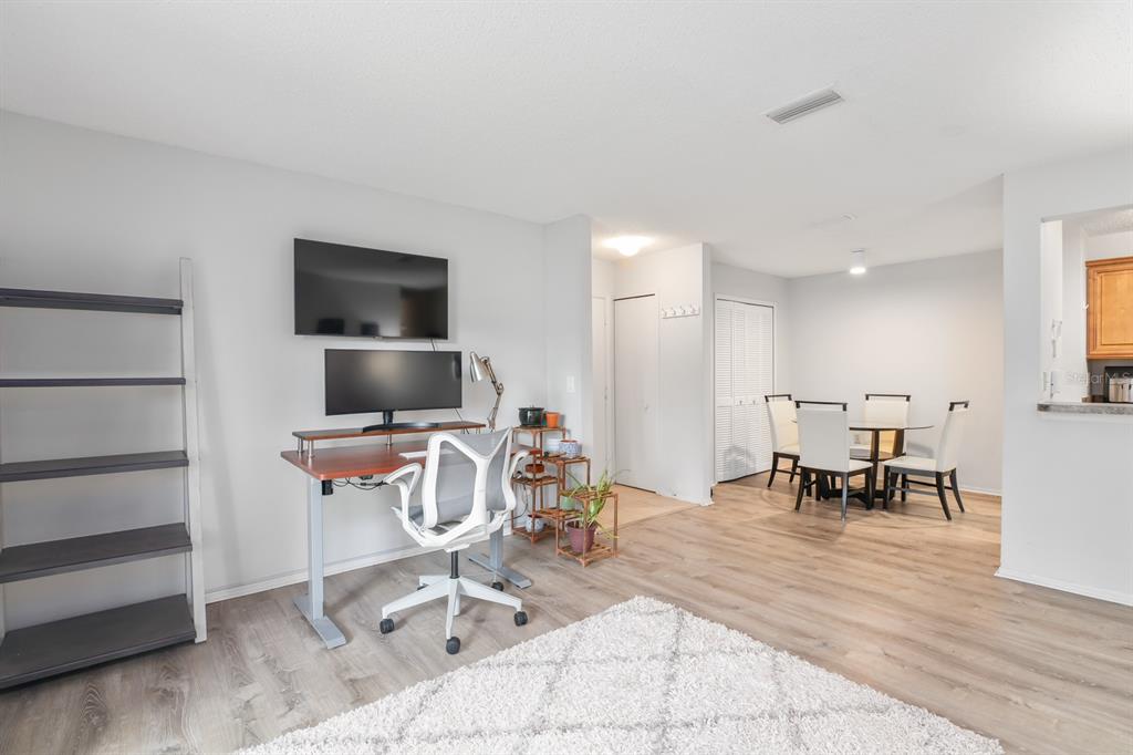 A living area featuring a desk, a wall-mounted television, and a dining table with chairs — 3705 SW 27TH STREET UNIT 1116, GAINESVILLE, FL