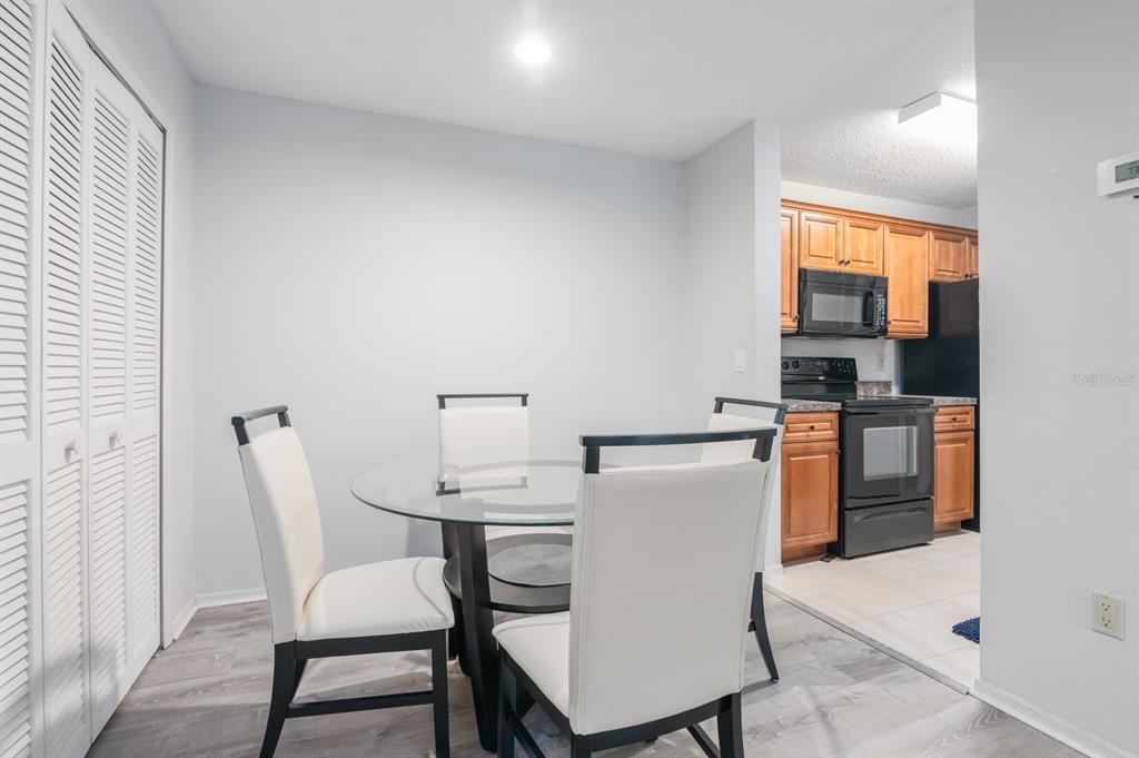 A dining area with a glass table and chairs sits adjacent to a wood-cabinet kitchen — 3705 SW 27TH STREET UNIT 1116, GAINESVILLE, FL