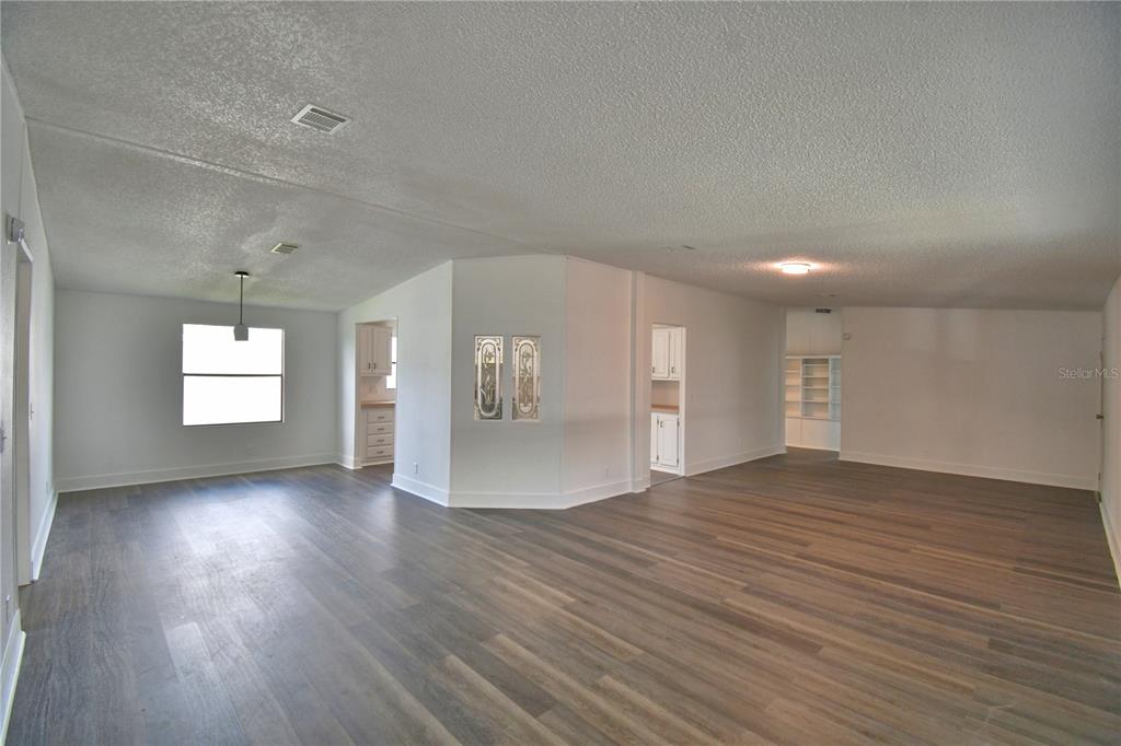 An open-concept living area features light gray walls, wood-look flooring, and white trim — 306 TOWNBRIDGE DRIVE, HAINES CITY, FL