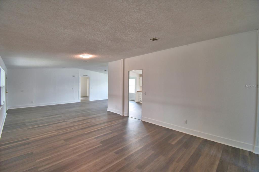 An empty room features white walls, dark wood-look flooring, and two doorways leading to other areas — 306 TOWNBRIDGE DRIVE, HAINES CITY, FL
