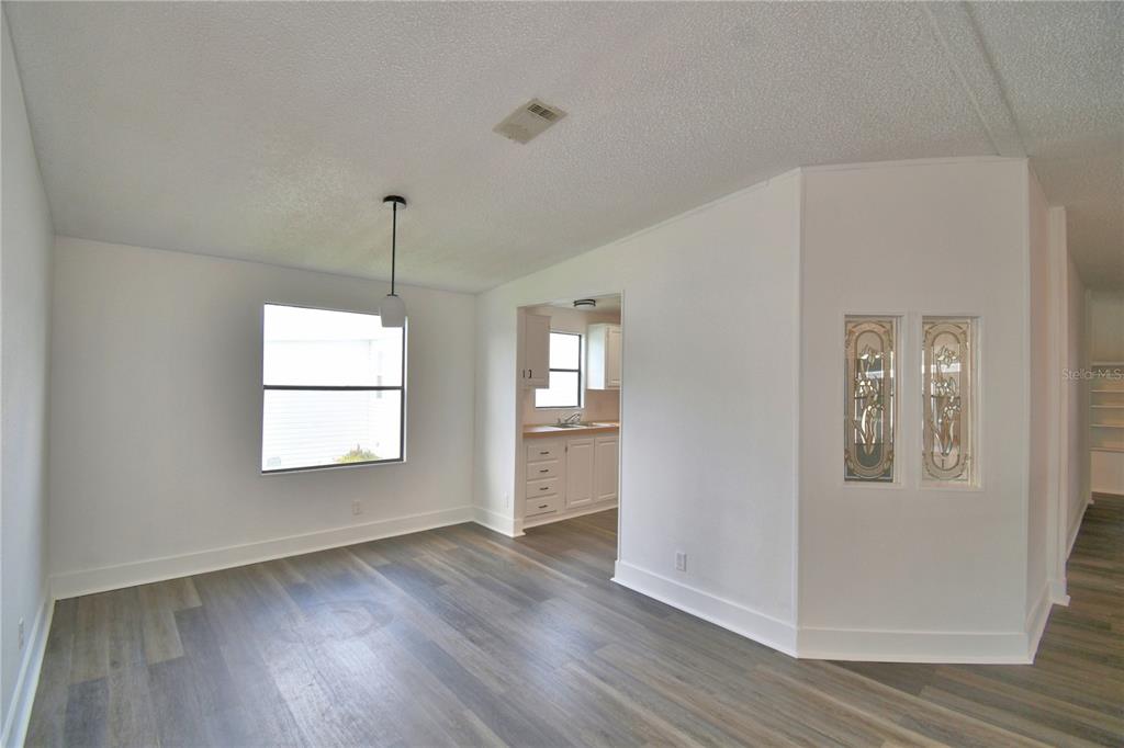A dining area with wood-look flooring, a pendant light, and a view into the kitchen — 306 TOWNBRIDGE DRIVE, HAINES CITY, FL