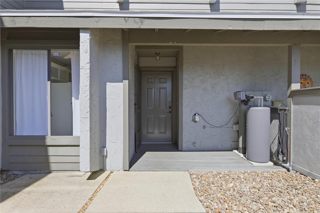 A gray front door is set in a stucco exterior wall with a water softener — 130 LIMEWOOD PLACE UNIT 3, ORMOND BEACH, FL