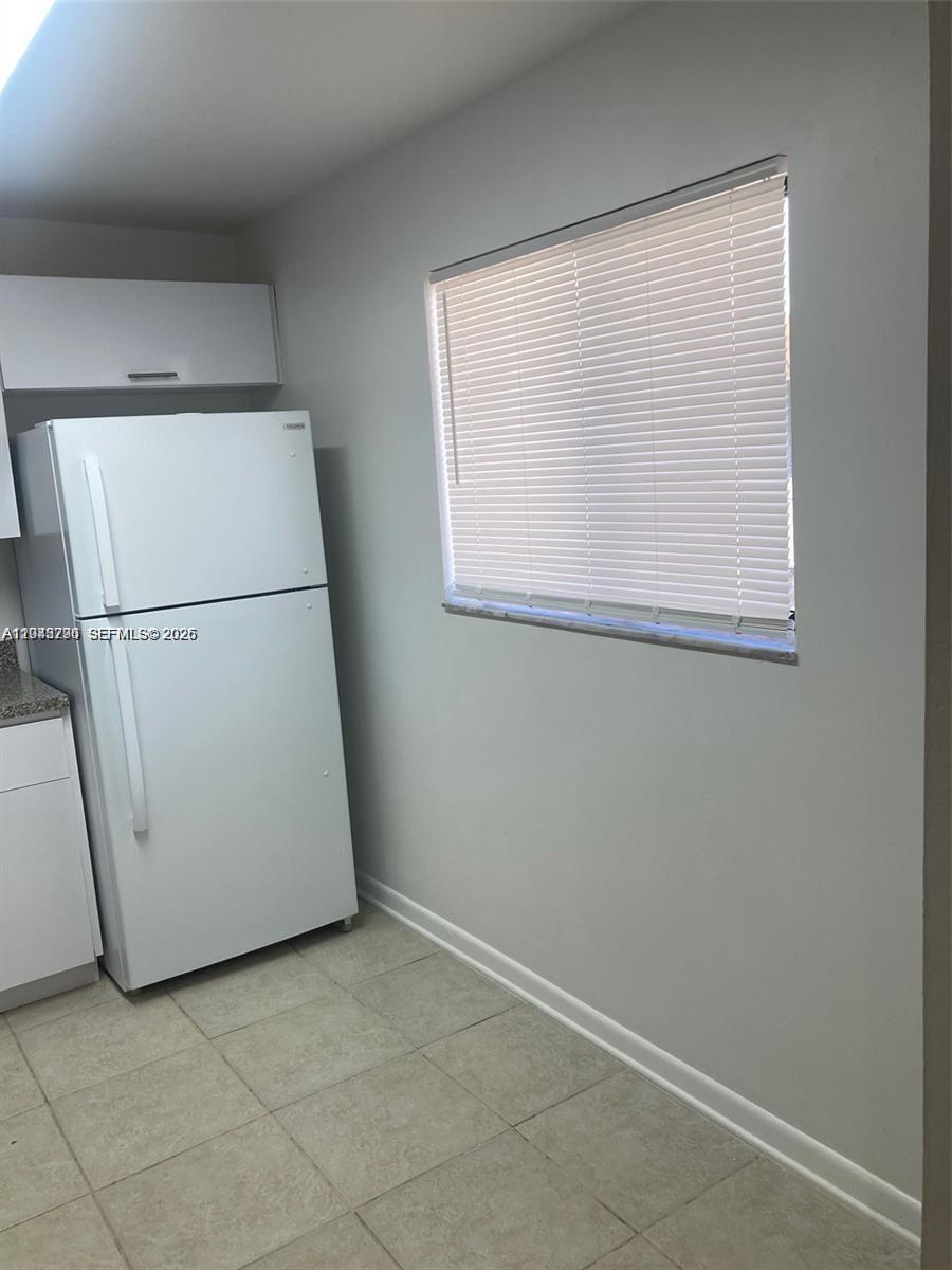 A kitchen features a white refrigerator, light-colored tile flooring, and a window with blinds — 8420 SW 133rd Ave Rd # 422, Miami FL 33183, MIAMI, FL