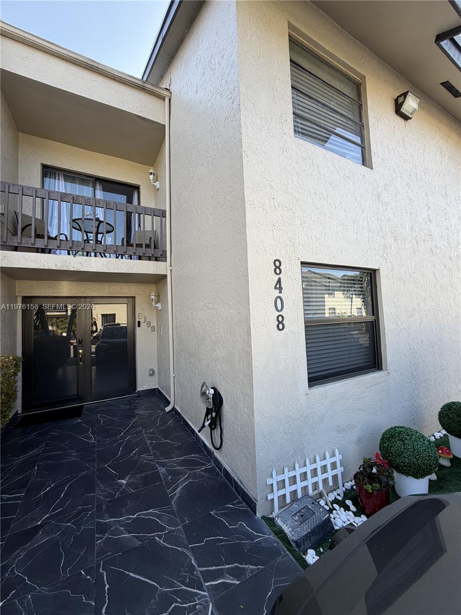 A two-story building exterior features a black tiled entryway, a balcony, and a window — 8408 NW 8th St # 8408, Miami FL 33126, MIAMI, FL