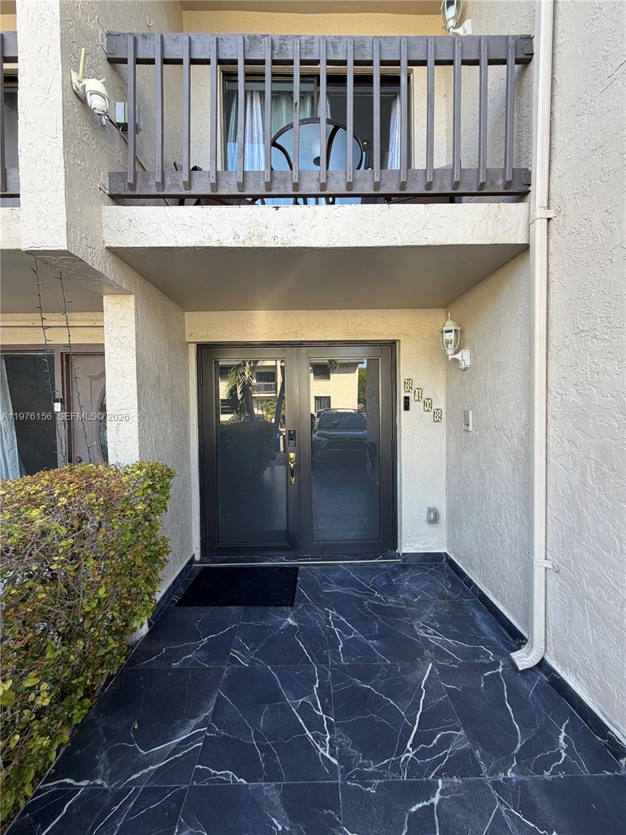 The exterior entrance features double glass doors, a black marble-tiled porch, and an upper balcony — 8408 NW 8th St # 8408, Miami FL 33126, MIAMI, FL