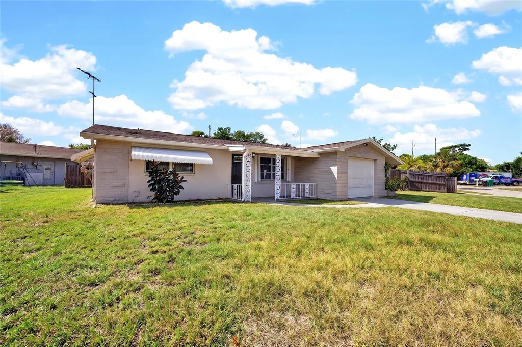A single-story house with a beige exterior, a front porch, and an attached garage — 10735 DARIUS STREET, PORT RICHEY, FL