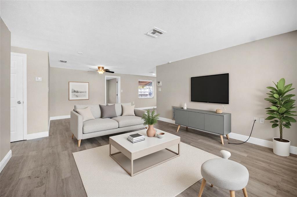 A living room with light gray flooring, a sofa, a coffee table, and a television — 10735 DARIUS STREET, PORT RICHEY, FL