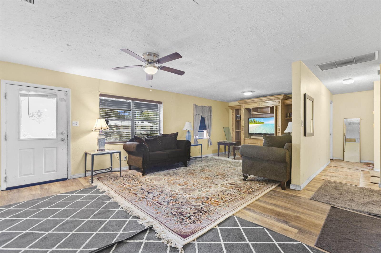 A living room features two dark sofas, a patterned area rug, and a large entertainment center — 3108 Mura Drive, Fort Pierce FL 34982, FORT PIERCE, FL