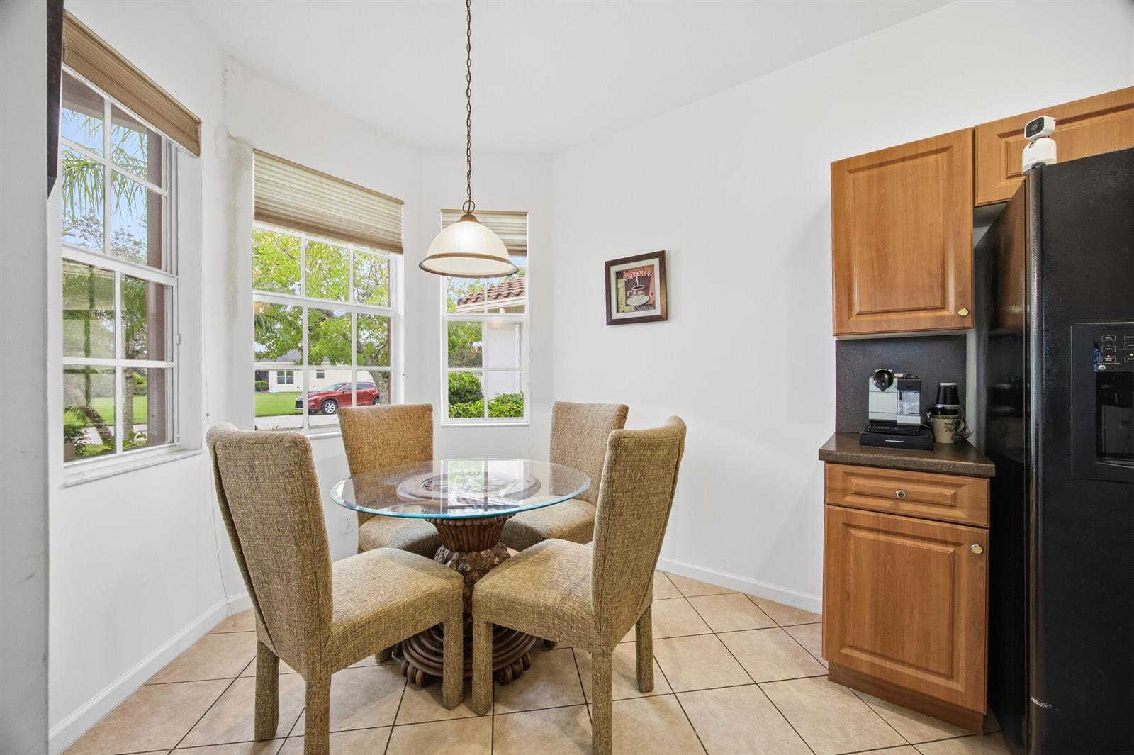 A breakfast nook features a glass-topped table, four upholstered chairs, tile flooring, and wood cabinetry — 11200 SW Birch Tree Circle, Port St. Lucie FL 34987, PORT ST. LUCIE, FL