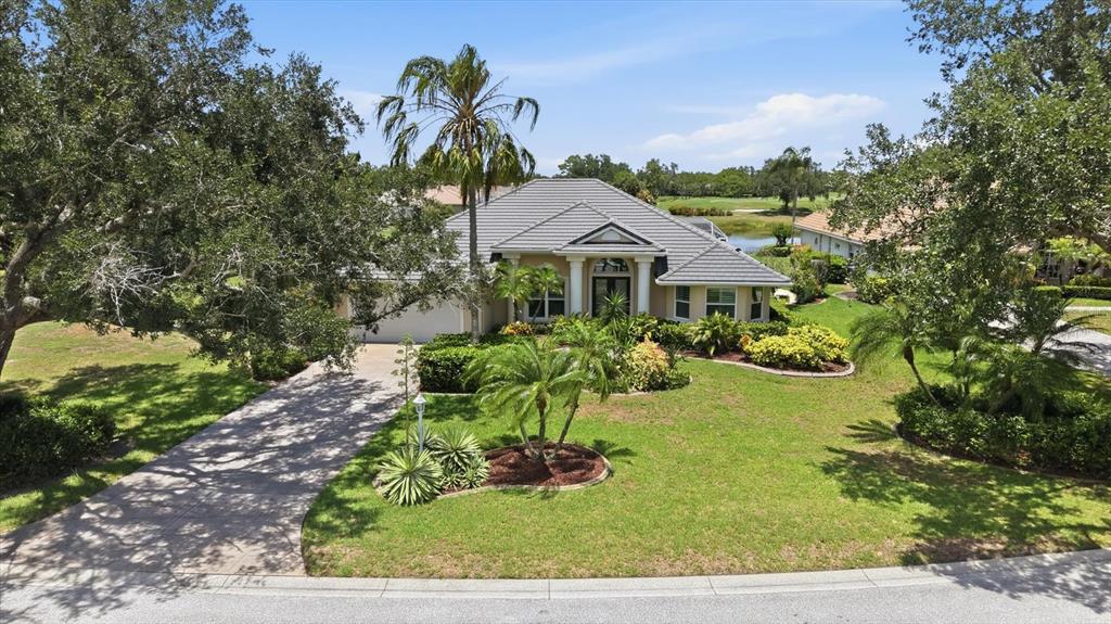 A single-story house with a gray tile roof and a paved driveway sits on a lawn — 7501 EATON COURT, UNIVERSITY PARK, FL