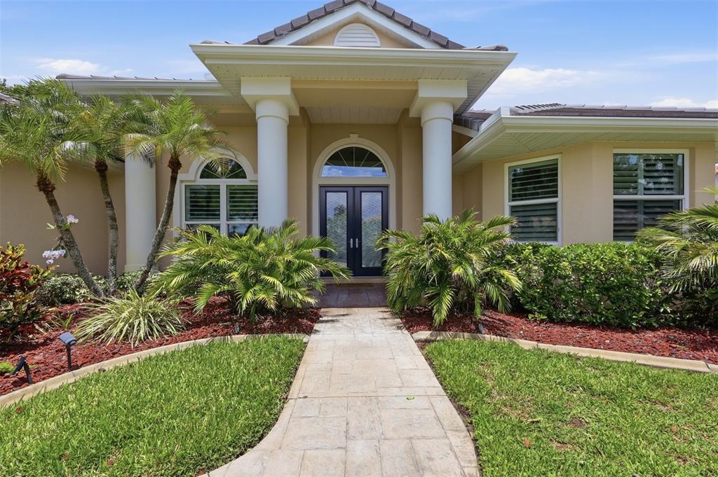 A stone walkway leads to the front entrance of a house with white columns — 7501 EATON COURT, UNIVERSITY PARK, FL