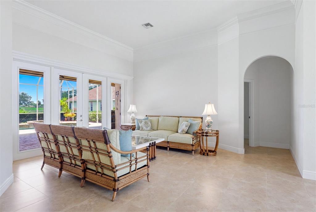 A living room with tile floors, wicker furniture, and glass doors opening to a pool area — 7501 EATON COURT, UNIVERSITY PARK, FL