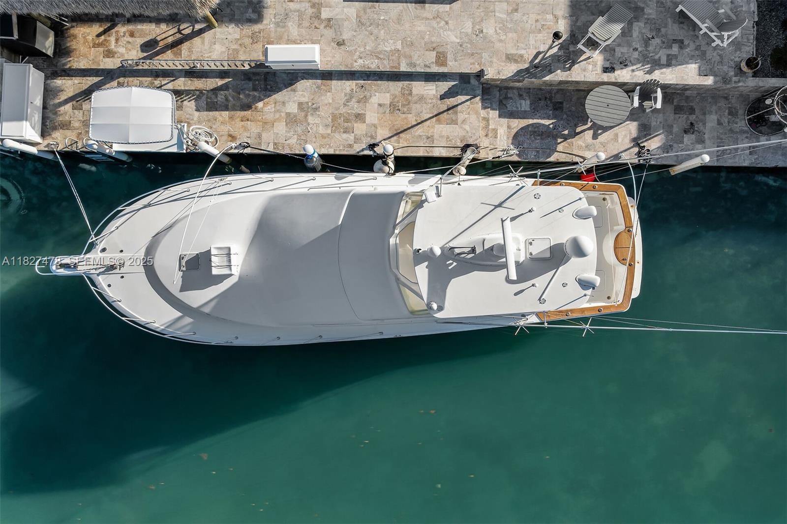 An aerial view shows a white yacht docked alongside a stone patio with outdoor furniture — 232 W Seaview Dr, Duck FL 33050, DUCK, FL
