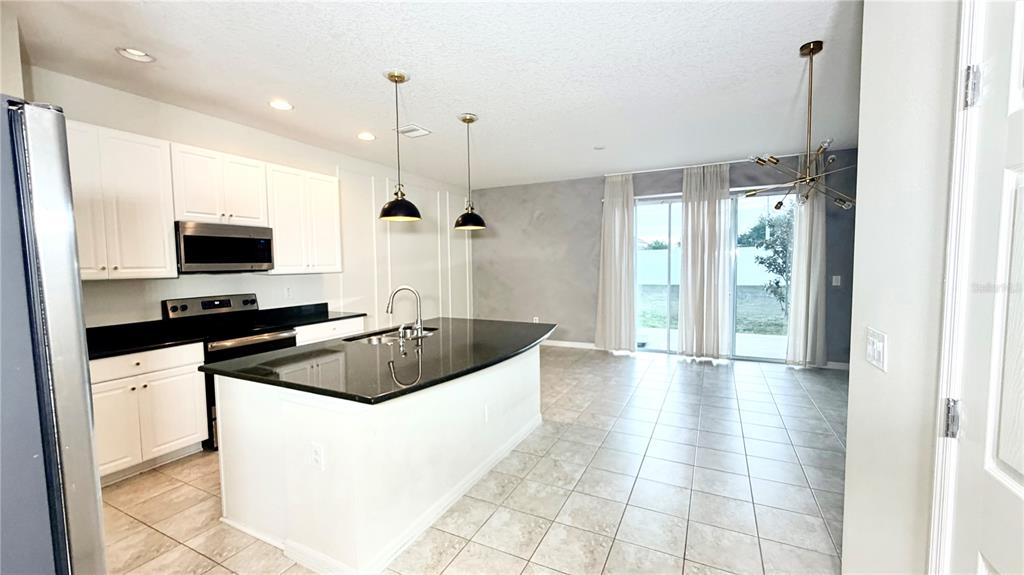 A kitchen with white cabinets, black countertops, a center island, and tile flooring — 7037 WOODCHASE GLEN DRIVE, RIVERVIEW, FL