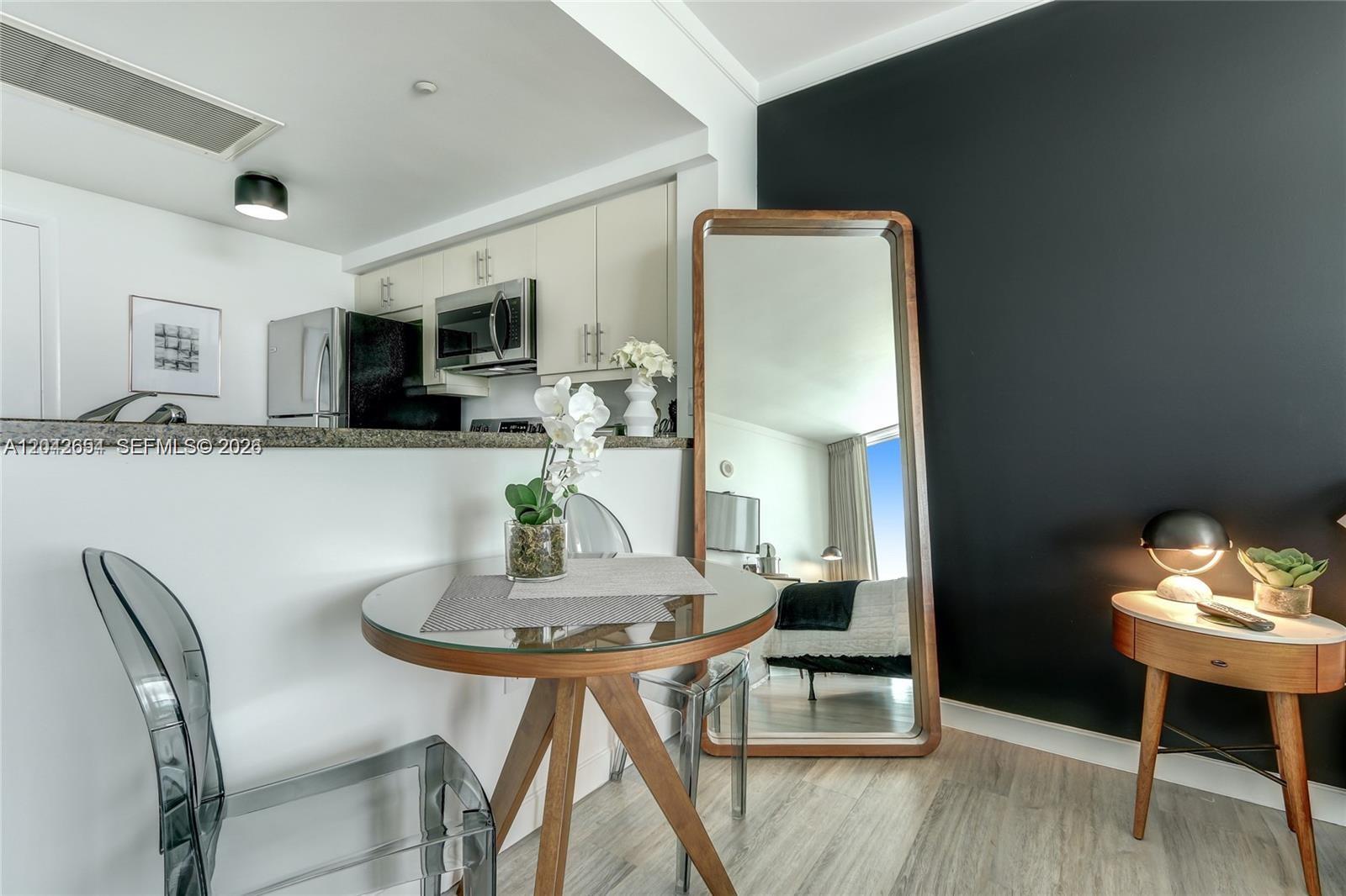 A dining area with a glass table, transparent chairs, and a large floor mirror — 2889 Mcfarlane Rd # 1811, Miami FL 33133, MIAMI, FL
