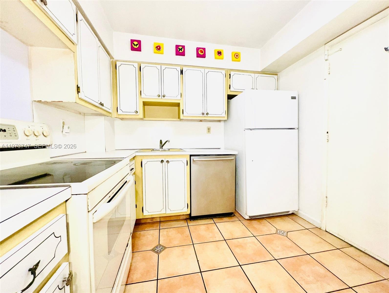 A kitchen features white cabinets, a stainless steel dishwasher, a white refrigerator, and tiled floors — 1658 Bay Rd # 203, Miami Beach FL 33139, MIAMI BEACH, FL