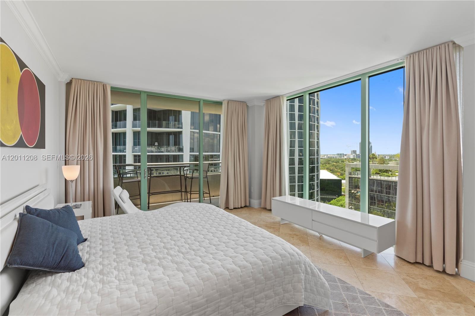 A balcony with a table and chairs overlooks modern high-rise buildings under a blue sky — 3400 SW 27th Ave # 1505, Coconut Grove FL 33133, COCONUT GROVE, FL