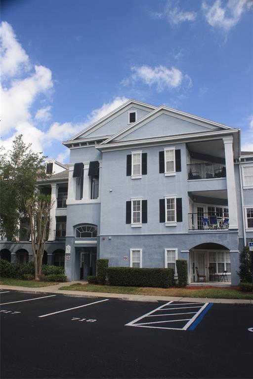 A three-story blue apartment building with white trim, balconies, and a paved parking lot — 3621 CONROY ROAD UNIT 739, ORLANDO, FL