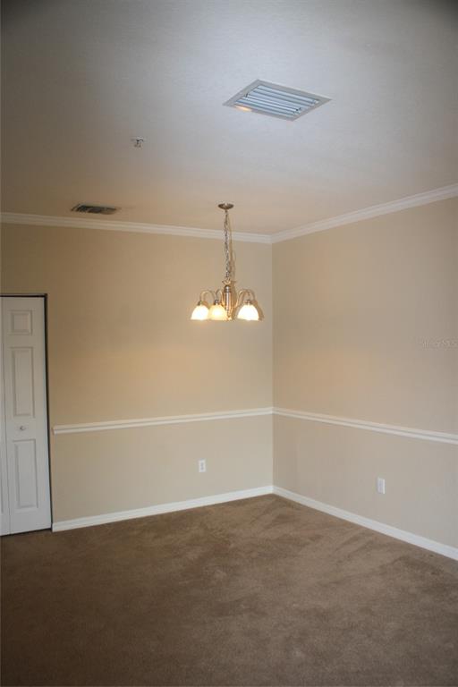 An empty dining room features beige walls with chair rail molding, carpeted floors, and a chandelier — 3621 CONROY ROAD UNIT 739, ORLANDO, FL