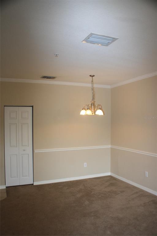 A dining room with beige walls, chair rail molding, a chandelier, and brown carpet — 3621 CONROY ROAD UNIT 739, ORLANDO, FL