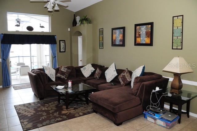 A living room features a large brown sectional sofa, a glass coffee table, and tile flooring — 8015 INDIAN CREEK BOULEVARD, KISSIMMEE, FL