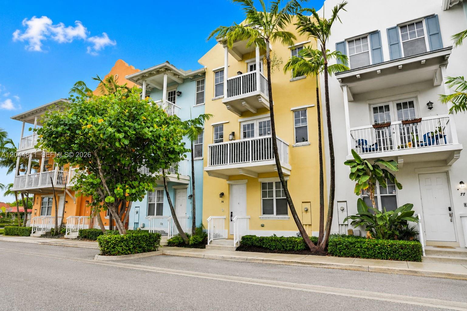 A row of colorful, multi-story townhouses features balconies, white railings, and palm trees — 810 N 3rd Ave N # 76, Lake Worth FL 33460, LAKE WORTH, FL