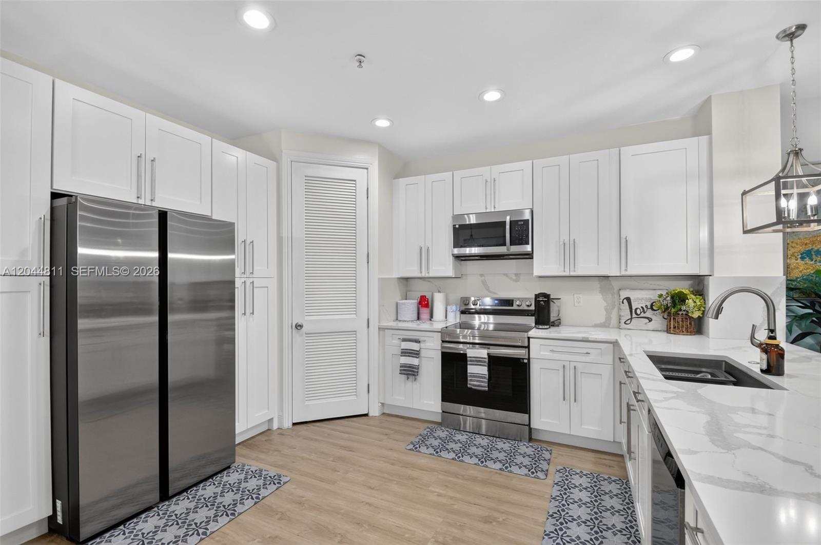 A modern kitchen features white cabinets, stainless steel appliances, and white marble-patterned countertops — 810 N 3rd Ave N # 76, Lake Worth FL 33460, LAKE WORTH, FL
