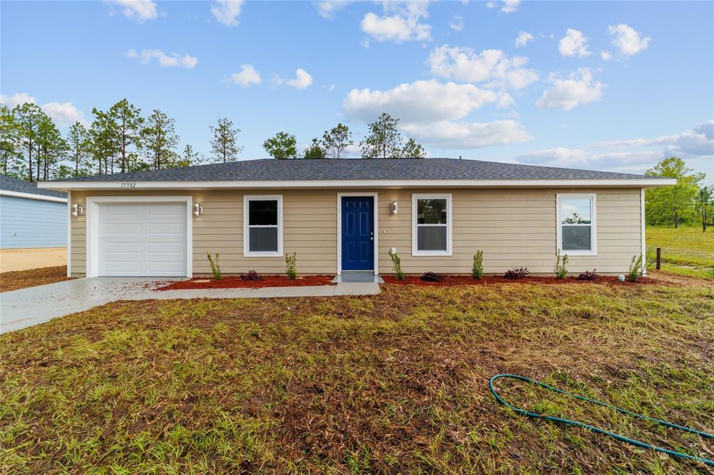 A single-story house with tan siding, a blue front door, and a one-car garage — 15776 SW 27TH LANE, OCALA, FL