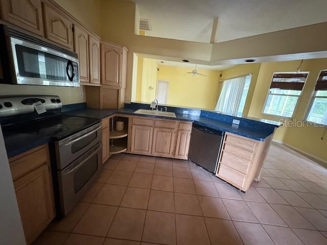 A kitchen features light wood cabinets, stainless steel appliances, and tile flooring — 711 128TH STREET NE, BRADENTON, FL