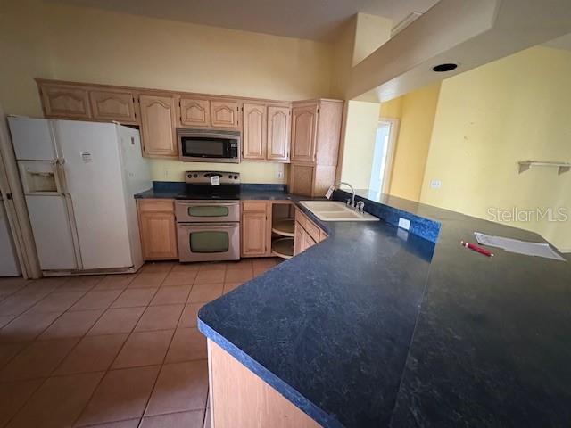 A kitchen features light wood cabinets, a white refrigerator, and a dark blue countertop — 711 128TH STREET NE, BRADENTON, FL