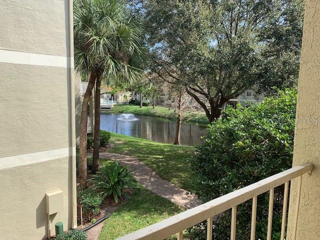 A view from a balcony overlooking a pond with a fountain and surrounding trees — 3016 PARKWAY BOULEVARD UNIT 204, KISSIMMEE, FL
