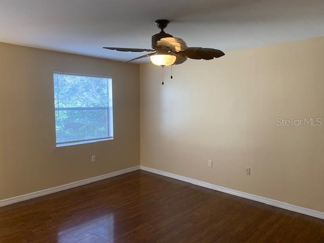 An empty room features light-colored walls, a ceiling fan, and dark wood-look flooring — 3016 PARKWAY BOULEVARD UNIT 204, KISSIMMEE, FL