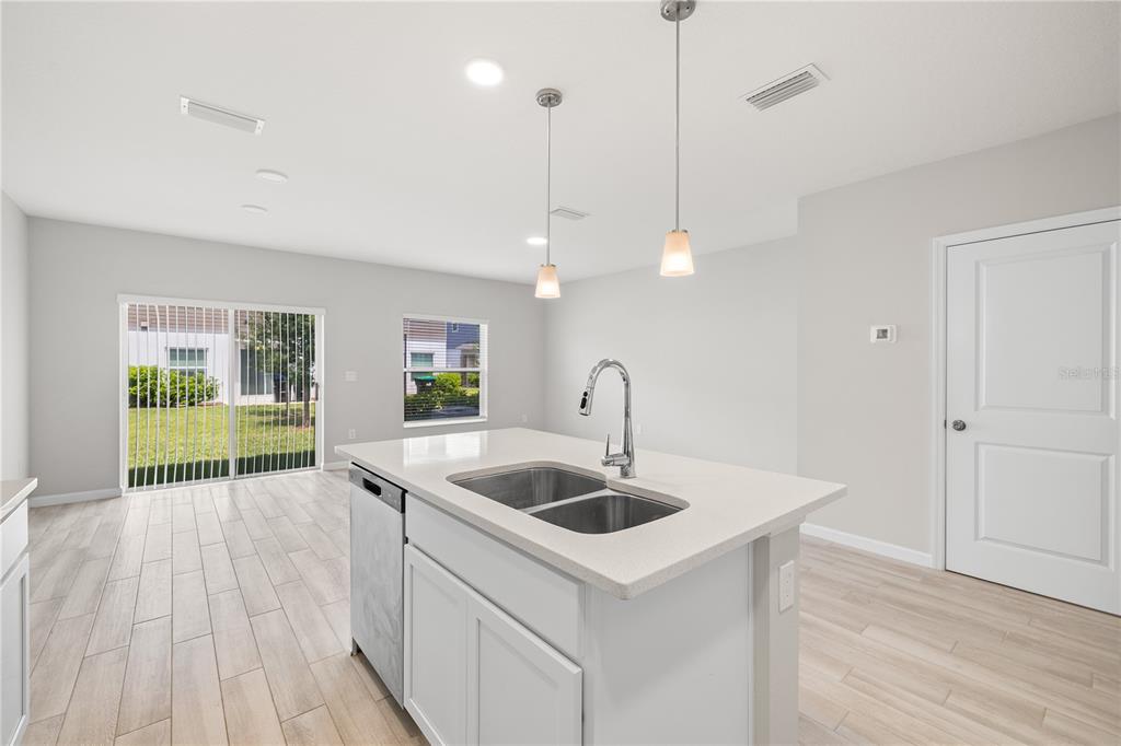 A kitchen island with a double sink sits in a room with light tile flooring — 14856 HARVEST STREET, ORLANDO, FL