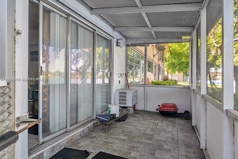 A screened-in patio features tiled flooring, a metal roof, and sliding glass doors — 19000 NE 3rd Ct # 405, Miami FL 33179, MIAMI, FL