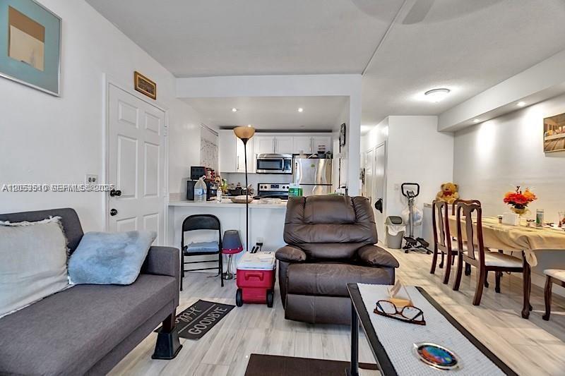 A living room with a gray sofa, a brown recliner, and an open kitchen area — 19000 NE 3rd Ct # 405, Miami FL 33179, MIAMI, FL