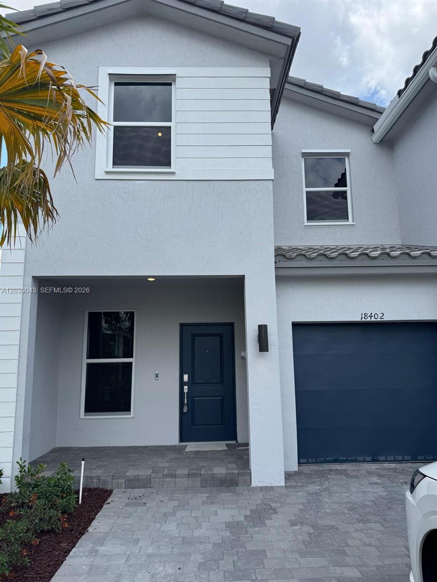 A two-story house features a gray stucco exterior, a dark blue front door, and a garage — 18402 SW 2nd St, Pembroke Pines FL 33029, PEMBROKE PINES, FL