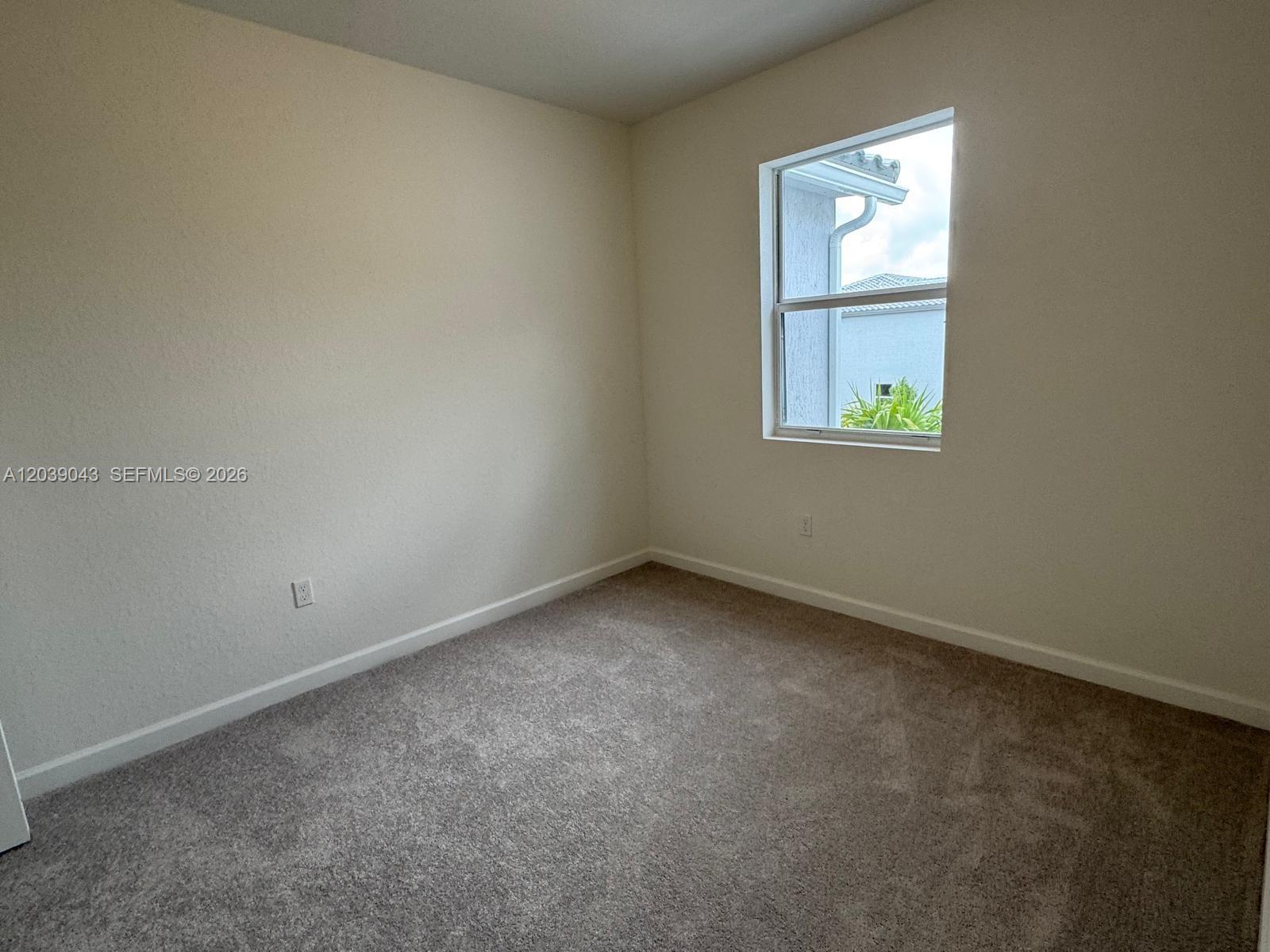An empty bedroom features beige walls, gray carpeting, and a single window — 18402 SW 2nd St, Pembroke Pines FL 33029, PEMBROKE PINES, FL