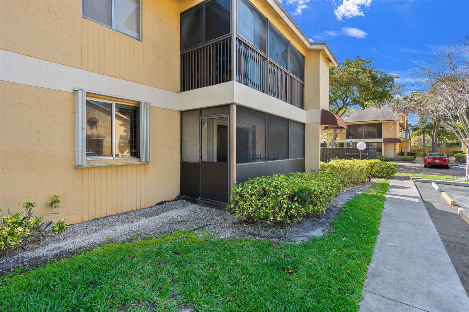 A two-story apartment building features a ground-floor screened patio and a second-story balcony — 3053 N Oakland Forest Drive # 102, Oakland Park FL 33309, OAKLAND PARK, FL